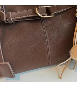 Detail of dark brown faux leather tote with fine grain texture and golden metal D-ring buckle