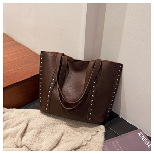 Detail of dark brown lychee leather tote bag featuring stylish silver rivet embellishments