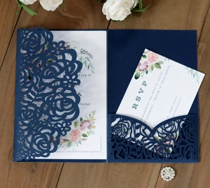 Detail of laser-cut navy blue wedding invitation with intricate rose texture and floral cards