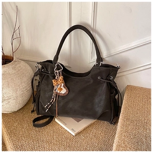 Detail view of black suede tote bag with drawstring sides and leopard print bow accent
