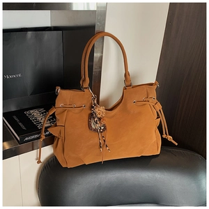 Detail of camel suede tote bag featuring leopard print tassel and side drawstring