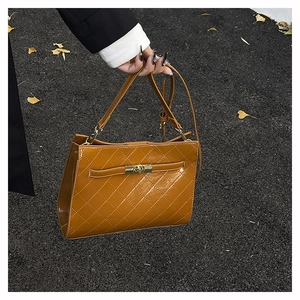 Caramel quilted leather underarm bag with gold twist lock on autumn street background