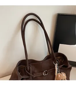 Detail of dark coffee leather tote bag with comfortable shoulder strap and plush bear charm