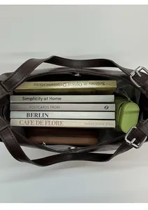 Top-down view of a spacious brown leather shoulder bag interior holding books and accessories