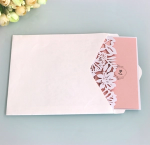 Close-up of laser-cut floral invitation with pink wedding insert and white envelope
