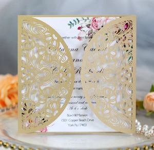 Detail of laser-cut gold wedding invitation with intricate lace patterns and floral inner card