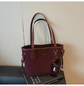 Détail du cabas bordeaux avec breloque boule en peluche marron et logo doré