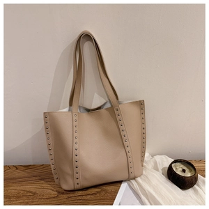 Detail of silver rivets on beige pebbled leather tote bag with a minimalist design