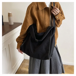 Macro detail of black oversized hobo bag with leather piping and soft fabric texture