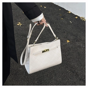 Detail of white quilted faux leather bag with gold twist lock and adjustable strap
