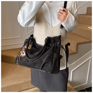 Detail of black suede tote bag with drawstring, adjustable strap and leopard print charm