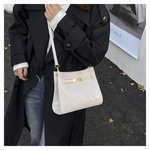 Detail of white quilted patent leather underarm bag with a golden turn-lock clasp