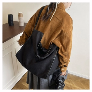 Detail view of a large black canvas shoulder bag showing durable fabric and wide strap