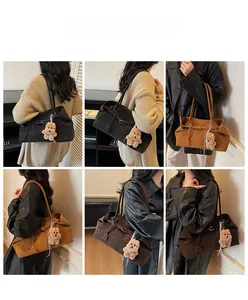 Detail of suede tote bag in black, caramel, and coffee with bear charm accessory