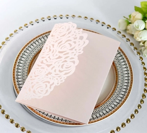 Detail of laser-cut rose patterns on elegant pale pink invitation card for weddings