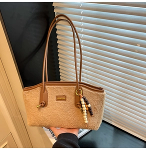 Details der warmbraunen Plüsch-Schultertasche mit Lederriemen und Holzperlen-Anhänger