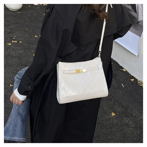 Close-up of a white quilted shoulder bag with gold twist lock on a black coat