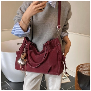 Detail of burgundy tote bag showing side drawstring design and soft high-density material