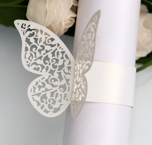 Detail of laser-cut butterfly napkin ring with intricate vine patterns on pearl paper