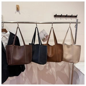 Detail view of large rivet tote bags in dark coffee, black, caramel, and cream colors