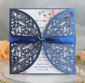 Laser-cut navy blue wedding invitation with elegant floral patterns and silk ribbon bow