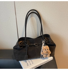 Detail of minimalist black matte suede tote bag with stylish buckle and puppy charm