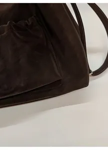Close-up of smooth dark brown leather texture and precise stitching on bag corner