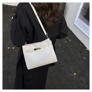 Outdoor model shot showing a white quilted shoulder bag with metal lock and chic PU leather finish