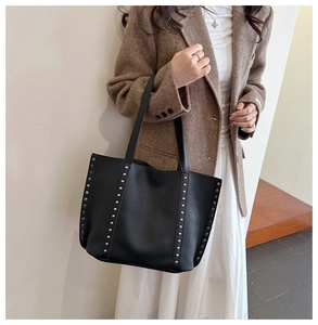 Detail view of black lychee leather tote bag featuring silver studs on the side