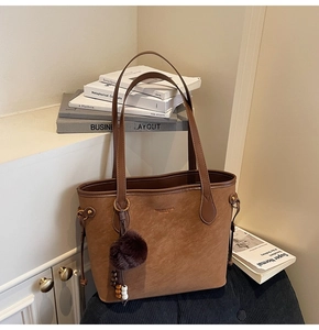 Détail d'un cabas en daim marron avec pompon en fourrure et perle en bois décorative
