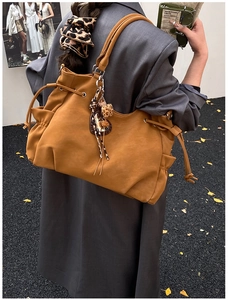 Detail view of brown PU tote bag with drawstring texture and leopard print accessory
