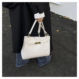 Detail of white quilted faux leather handbag with gold metal lock and elegant stitching