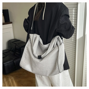 Detail view of a large grey textured fabric tote bag worn as a shoulder bag