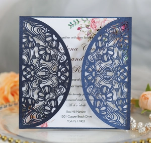 Detail view of laser-cut wedding invitation with elegant floral inner page and blue sleeve