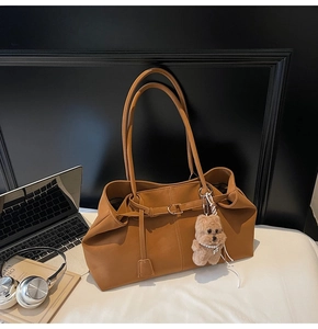 Detail of a brown suede tote bag with laptop and books in a modern work setting