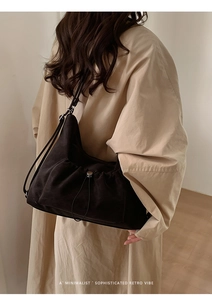 Detail of black drawstring underarm bag with pleated texture on trench coat