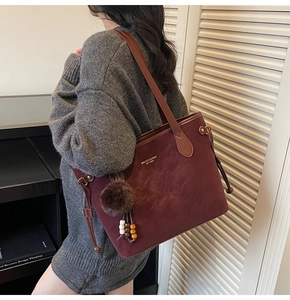 Détail du sac cabas en daim bordeaux avec pompon en fourrure et breloque perlée