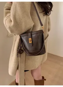 Detail view of dark brown vintage bucket bag with gold twist lock and crossbody strap