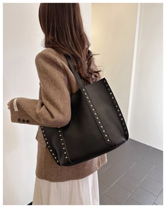 Detail view of large black tote bag with silver studs and premium pebble leather texture