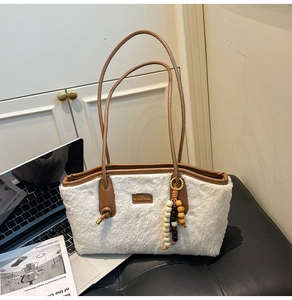 Detail der weißen Plüsch-Tasche mit braunen Ledergriffen und Holzperlen-Anhänger