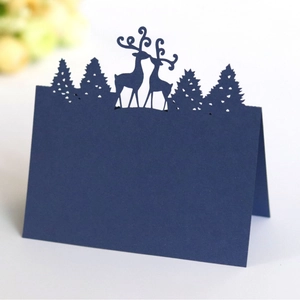 Laser-cut navy blue Christmas reindeer and pine tree place card on white surface