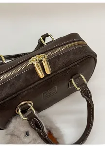 Close-up of smooth double gold zippers and litchi texture on retro coffee pillow bag