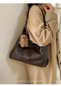Detail of dark brown hobo bag in soft matte leather with a cute plush bear charm