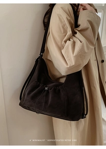 Side view of a large dark brown suede tote bag with drawstring detailing on a model