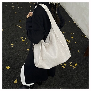 Chic beige hobo shoulder bag with linen texture carried by a model on a ginkgo street