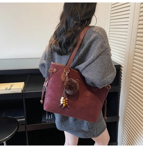 Femme portant un grand sac cabas bordeaux mat avec pompon en peluche et perles