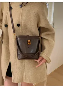 Detail of dark brown matte leather bucket bag with gold twist lock and embossed logo