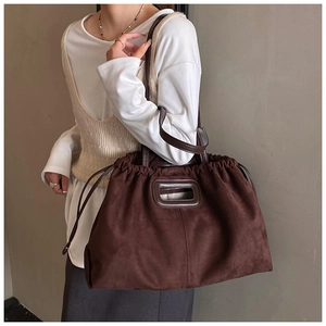 Détail du sac cabas en daim marron foncé avec cordon de serrage et poignée en cuir