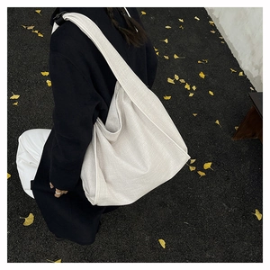 Minimalist beige oversized hobo bag on autumn ginkgo leaves background, street style view