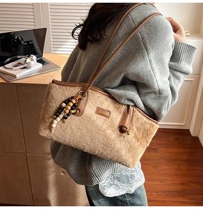 Plüsch-Schultertasche mit Lederriemen und dekorativen Holzperlen in Wohnumgebung